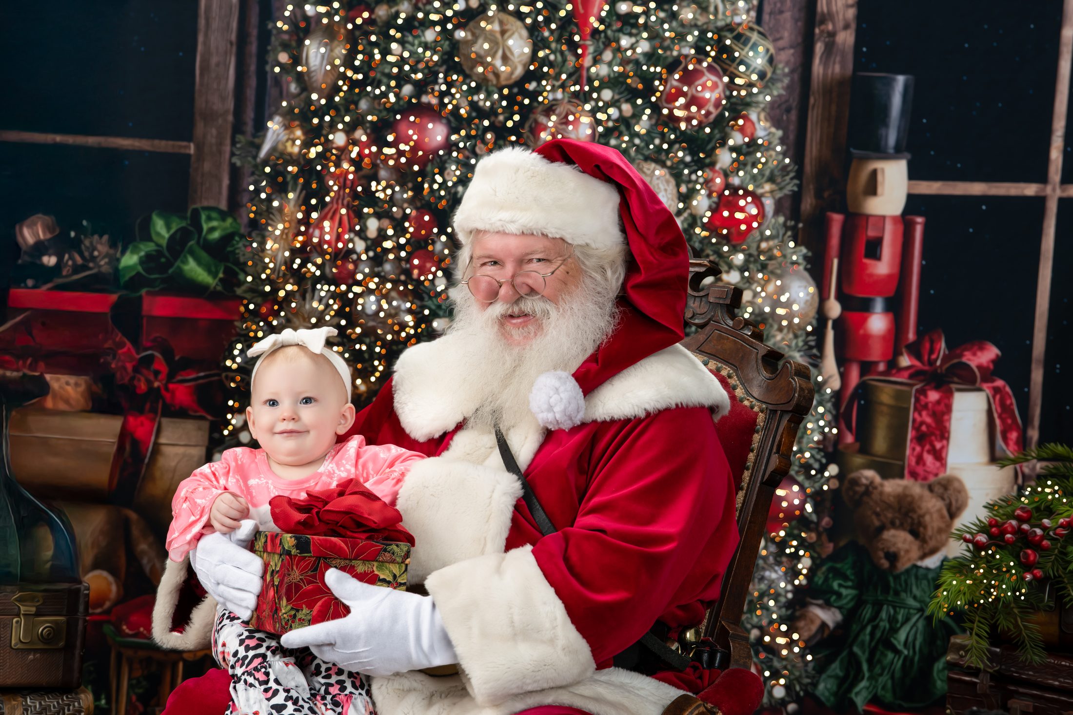 A little girl holding a wrapped gift on Santa's lap, a Blackwater fine art Christmas portrait